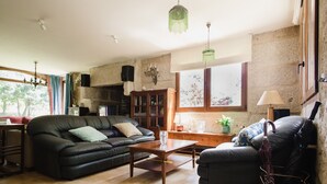 A living room with a black leather sofa, a wooden coffee table, a black armchair, and a green hanging light fixture.