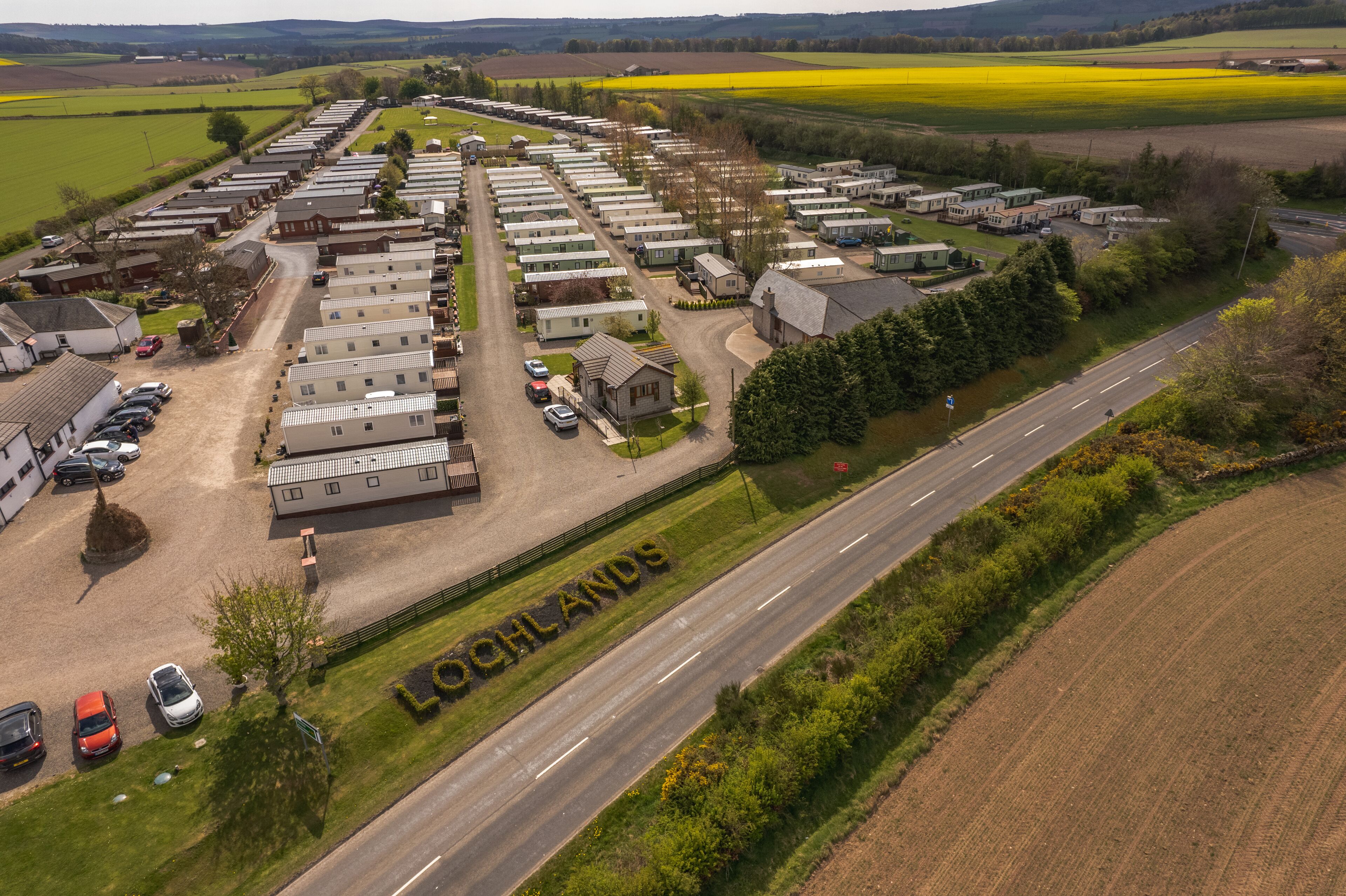 A large caravan park with multiple caravan sites, a main road, and surrounding agricultural fields.
