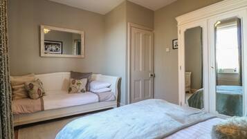 A bedroom with a bed, a sofa, a wardrobe, and a mirror.