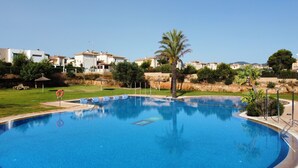 Une piscine équipée d’une bouée de sauvetage, entourée d’une pelouse et de palmiers.