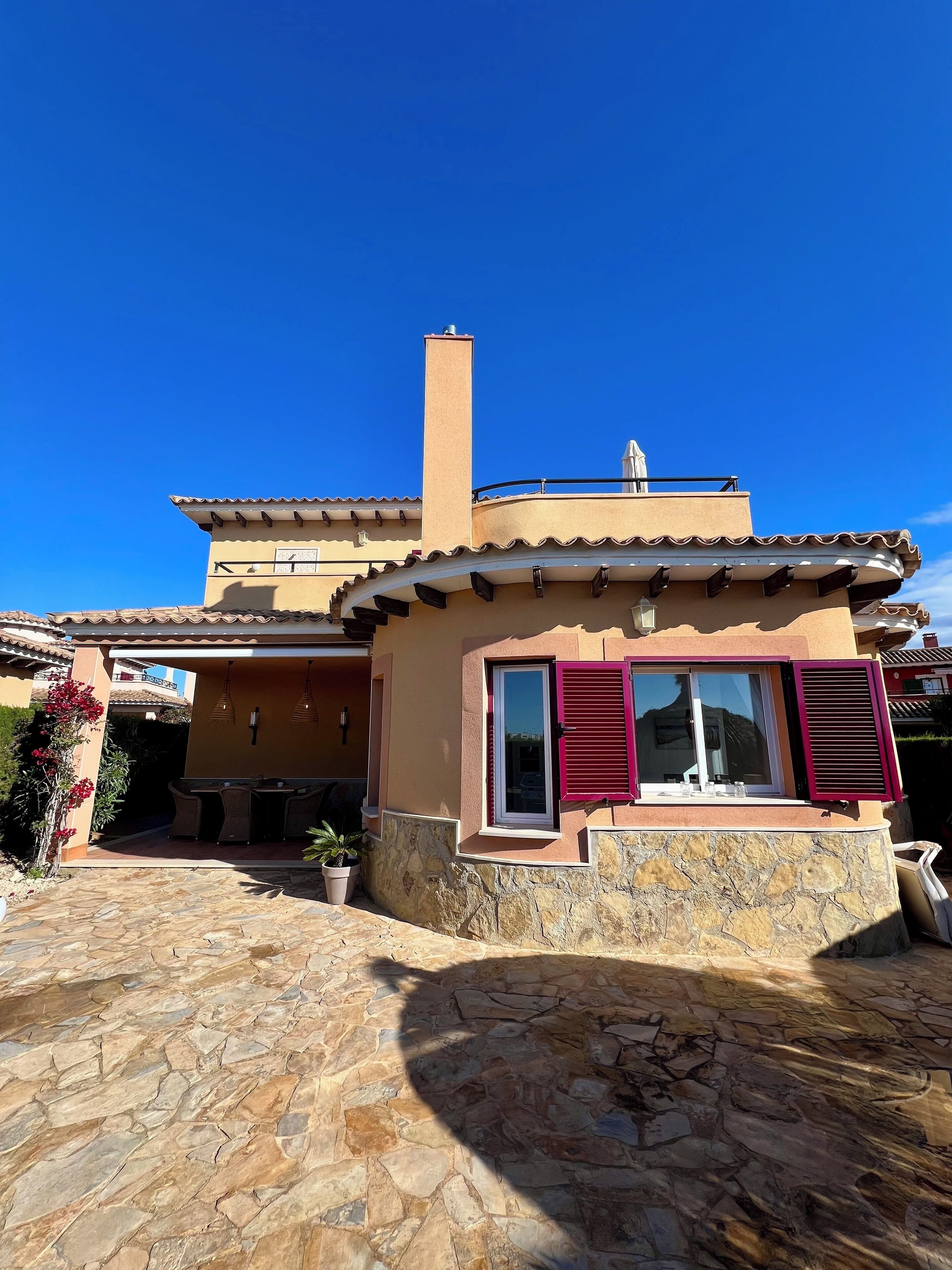 A two-story house with a stone foundation, a tiled roof, and a balcony.