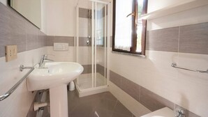 Une salle de bain avec une douche, un lavabo et une fenêtre.