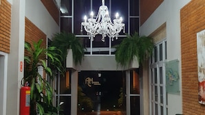 A hotel lobby with a chandelier, potted plants, a fire extinguisher, and a red carpet. - Ancona Center Hotel (Amparo)