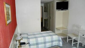 A bedroom with a bed, a desk, a chair, a television, and a wardrobe.