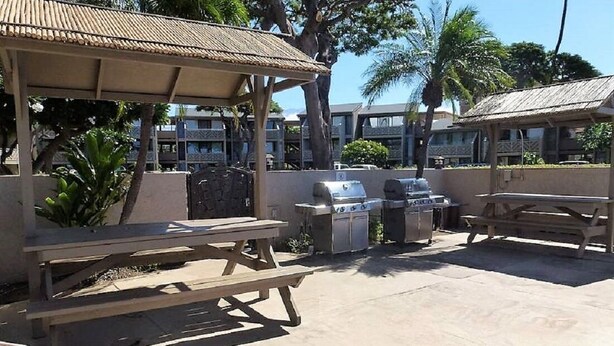 An outdoor patio with a pool, picnic tables, and barbecue grills. - Ground Floor Steps to beach! - Kihei Holiday 113 (Kihei)