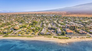 An aerial view of a coastal residential area with houses, roads, and a beach.