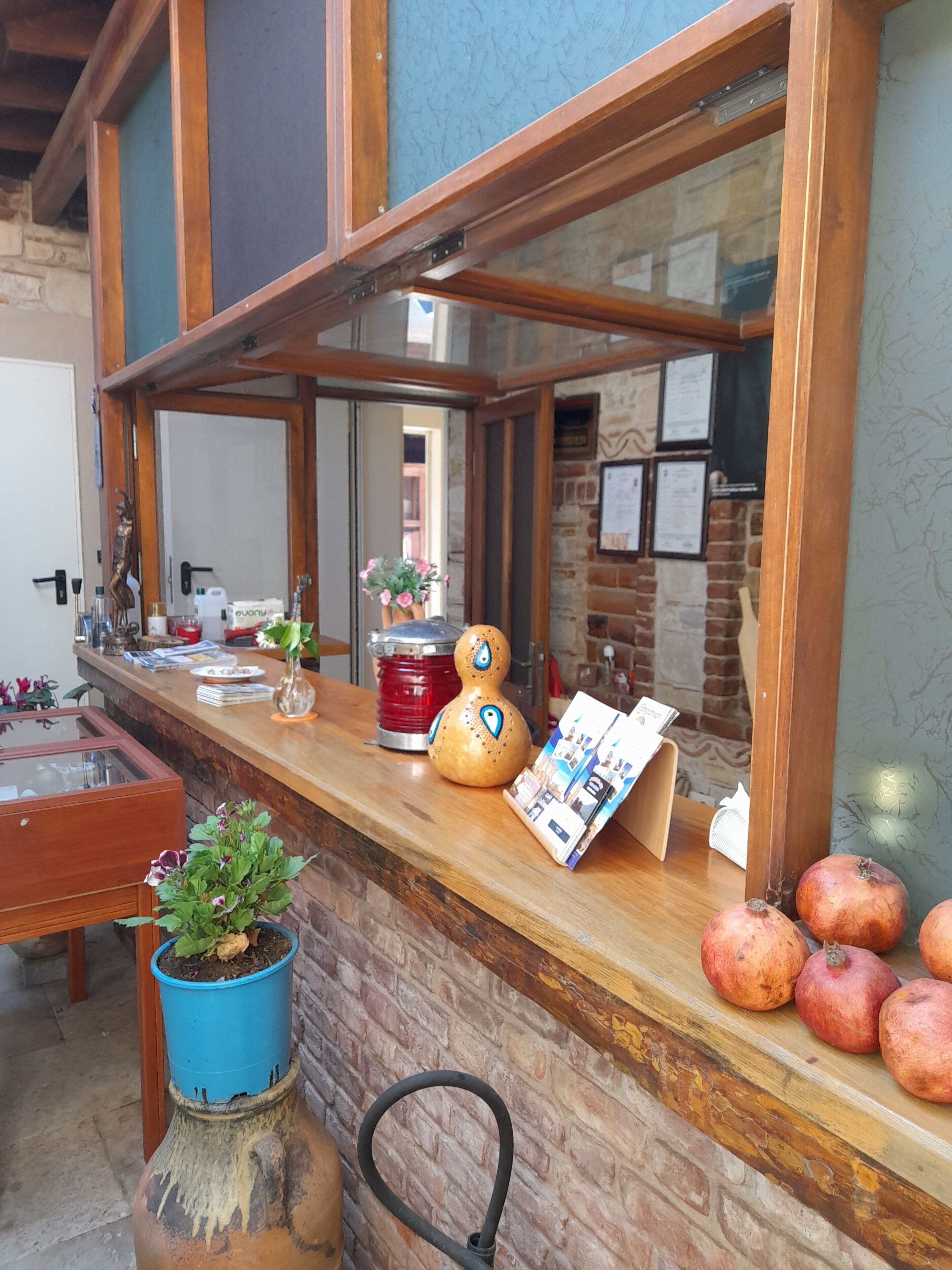 A wooden counter with a glass display, potted plants, and a menu board.