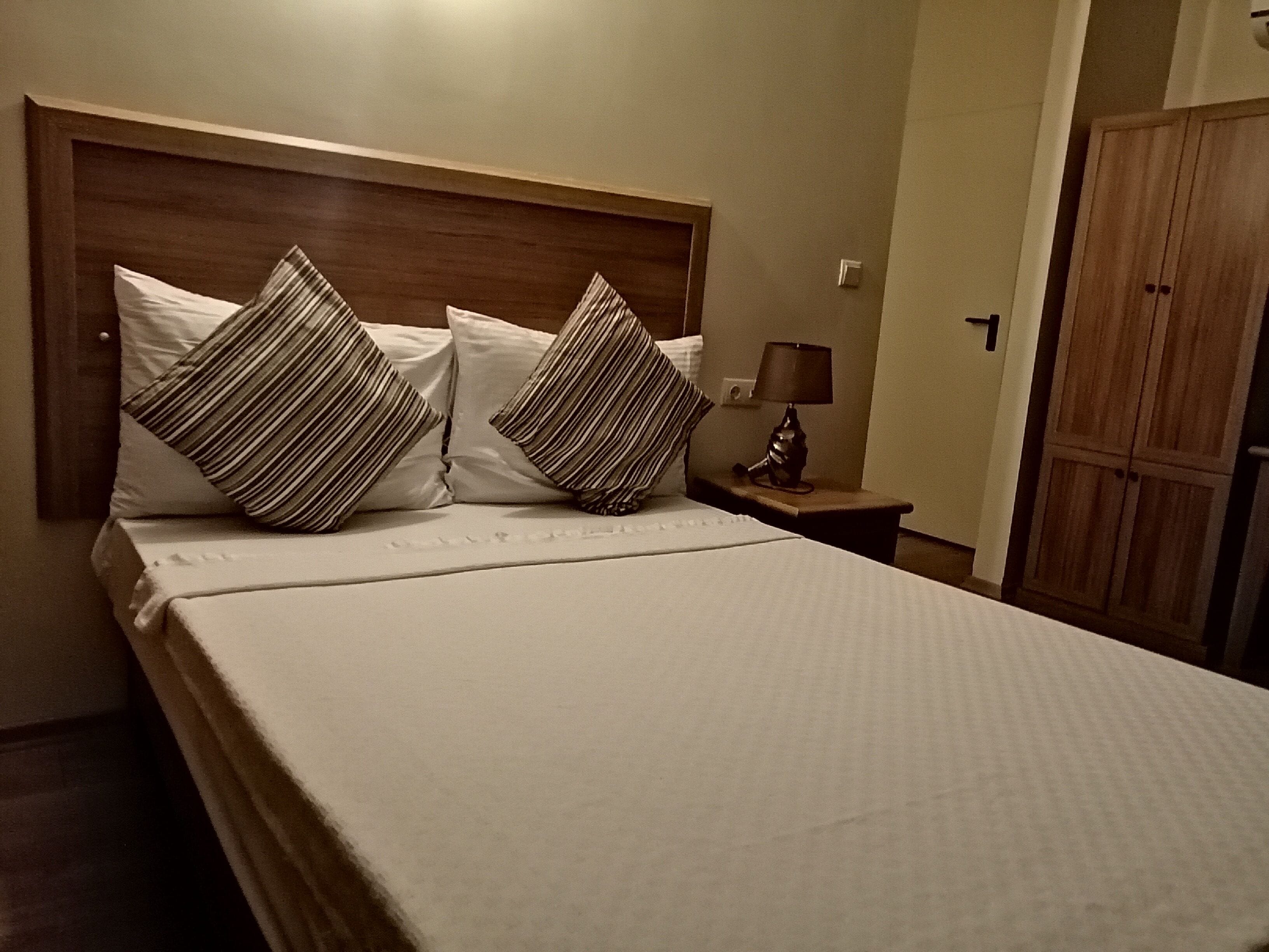 Una cama bien hecha con almohadas a rayas y un cabecero de madera.