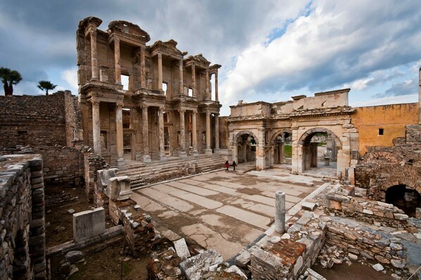 Un'antica rovina con colonne e archi, caratterizzata da un percorso in pietra e un piccolo cortile.