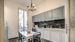 Una cocina moderna con armarios blancos, salpicadero negro y un comedor con mesa y sillas.