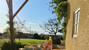 A wooden table set outdoors with croissants, bowls, and bottles of juice.