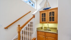 A staircase with wooden railings and a kitchen area with wooden cabinets and a granite countertop.