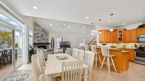 A spacious kitchen with wooden cabinets, a dining area with white chairs, and a large island with bar stools.