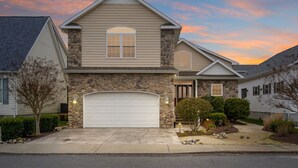 A two-story house with a stone facade, a garage, and a well-maintained front yard.