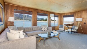 A modern living room with a sofa, coffee table, and lamps. Large windows offer a view of the water and hills. - Views for miles of the  Ocean and Bolinas Lagoon (Bolinas)