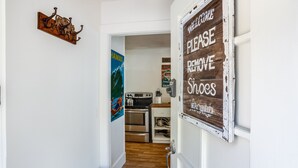A hallway leading to a kitchen with a 'Please Remove Shoes' sign, a 'Welcome' sign, and a 'Hawaii' poster. - Views for miles of the  Ocean and Bolinas Lagoon (Bolinas)