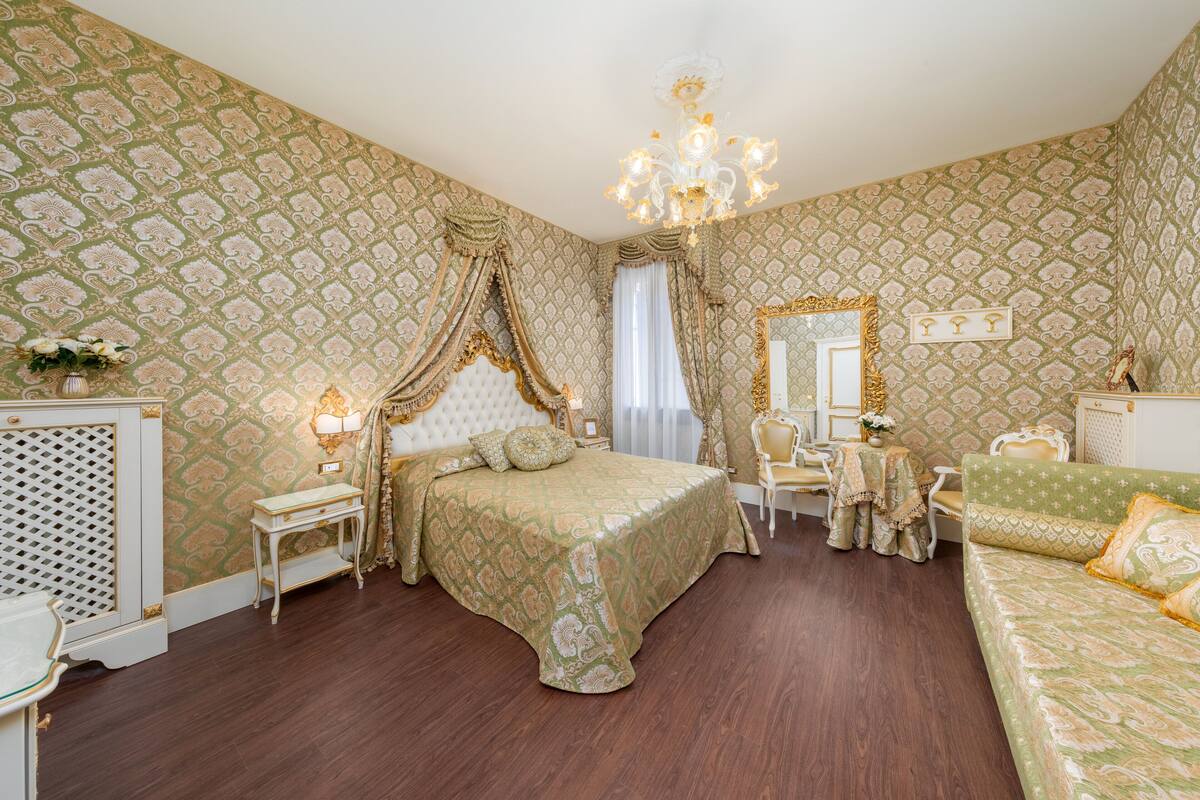 Un dormitorio lujoso con una cama grande, un tocador con espejo y un sofá verde.