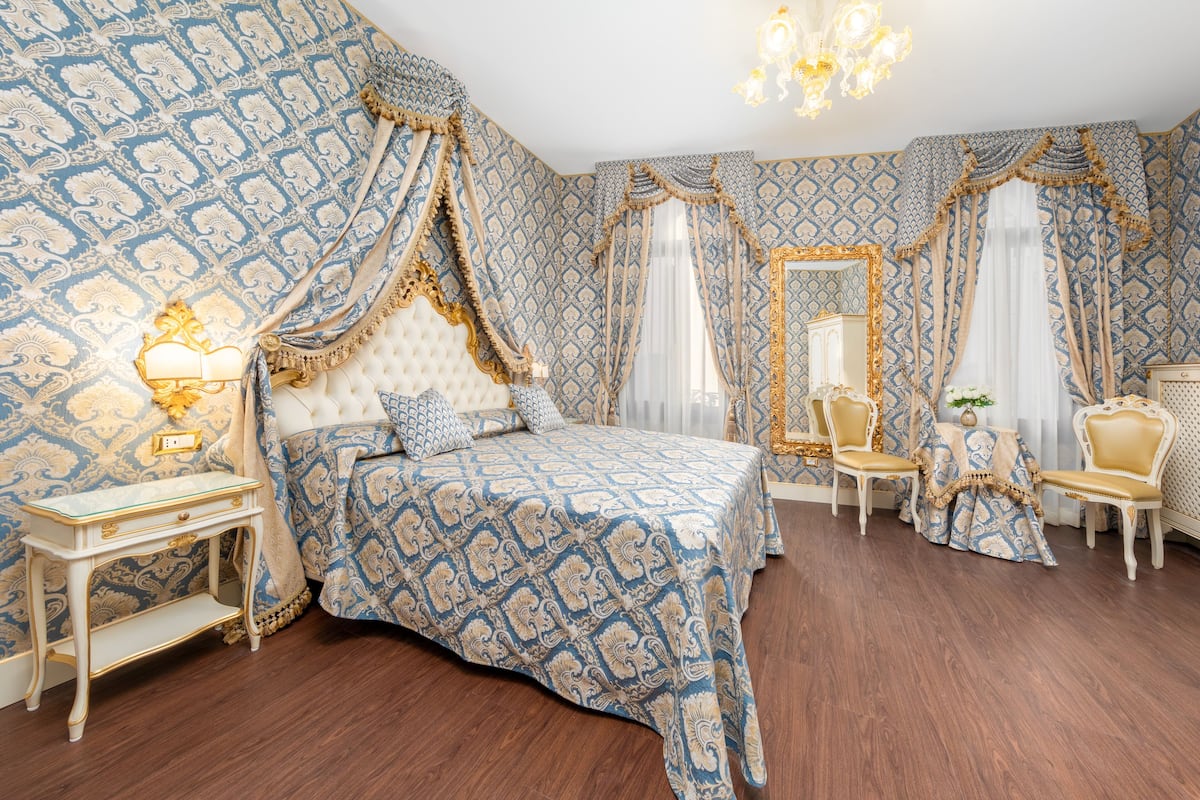 Un dormitorio con una cama grande, cortinas ornamentadas y muebles clásicos.