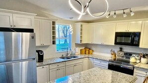 Eine moderne Küche mit weißen Schränken, Edelstahlgeräten, Granitarbeitsplatten und einem eingebauten Backofen.