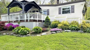 Ein zweistöckiges Haus mit überdachter Veranda und einem gepflegten Garten.