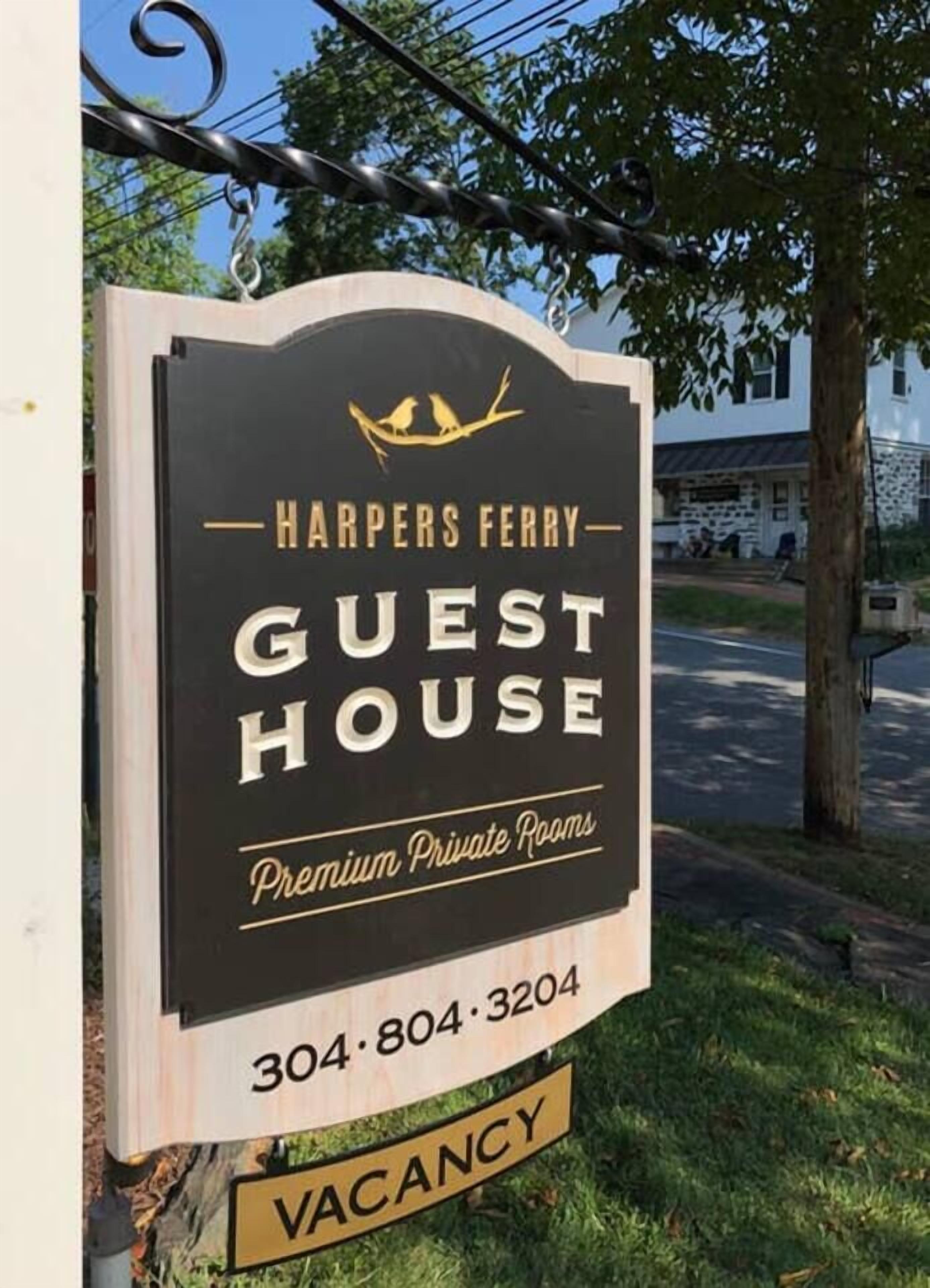 A sign for Harpers Ferry Guest House advertising premium private rooms with a vacancy notice.