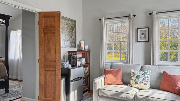 Un salon chaleureux avec un canapé gris, une table basse et une porte en bois donnant sur une autre pièce.