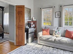 Un salon chaleureux avec un canapé gris, une table basse et une porte en bois donnant sur une autre pièce.