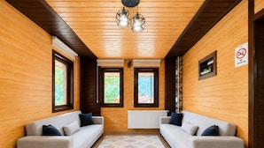 Una habitación con dos sofás, un tapete estampado, paredes de madera y un cartel de 'No Fumar'.