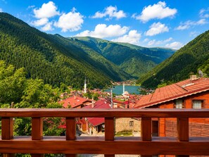 A mountainous landscape with a village, red-roofed buildings, and a prominent white tower.