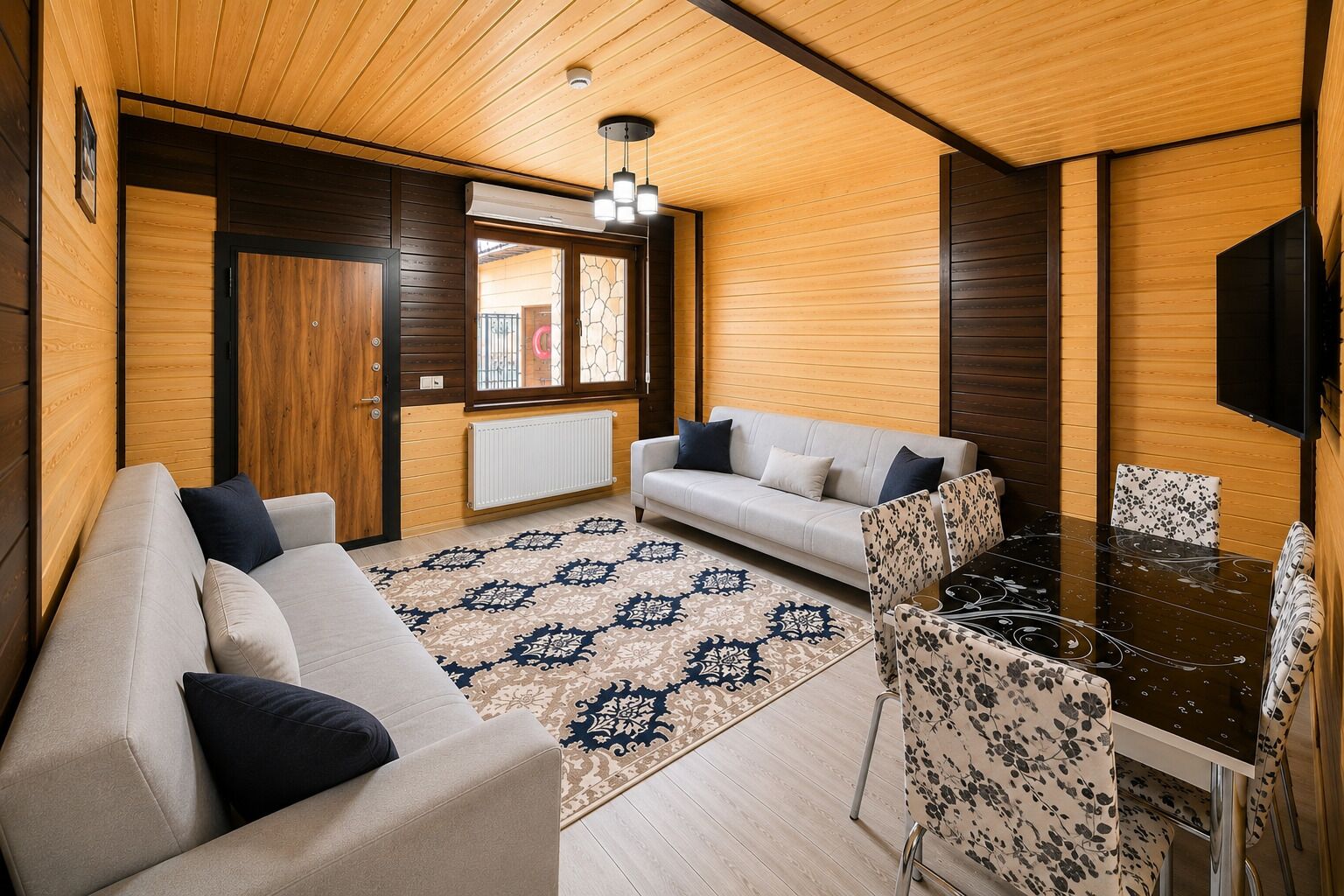 A cozy room with a sofa, a dining table, and a patterned rug.