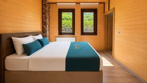 Un dormitorio con cama, dos ventanas, un radiador y paredes de madera.