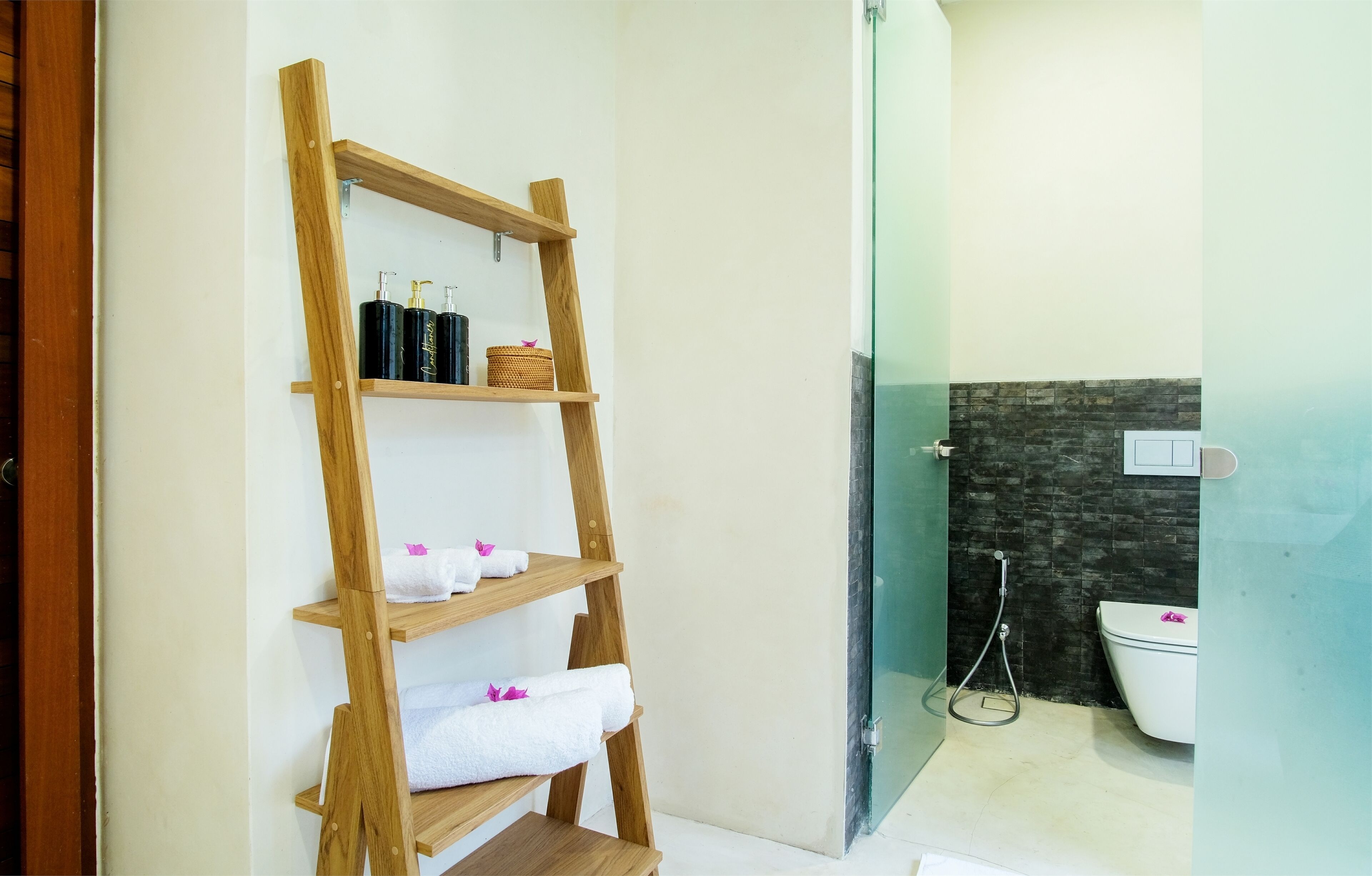 Un baño con un estante de madera que contiene toallas y artículos de aseo.