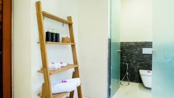 Un baño con un estante de madera que contiene toallas y artículos de aseo.