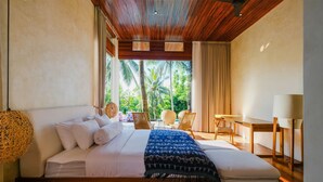 Een slaapkamer met een bed, een bureau en uitzicht op palmbomen.