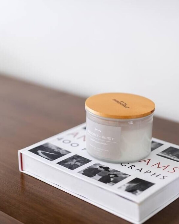 A candle with a white label and a brown lid on a book titled "AMS GRAPHICS". - The Rosemont III - Upscale 2BR Near the Beach (San Diego)