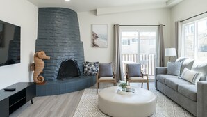 Una sala de estar moderna con chimenea de piedra, asientos cómodos y un amplio ventanal con vistas.