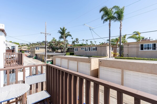 Zona residencial con casas, palmeras y un balcón con mesa y sillas.