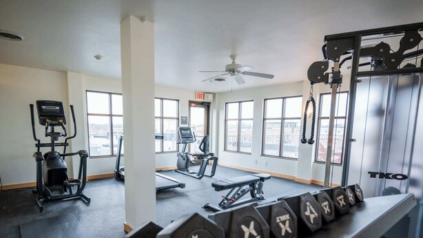 Une salle de sport équipée de tapis de course, de vélos elliptiques et de poids libres.