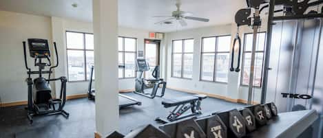 Une salle de sport équipée de tapis de course, de vélos elliptiques et de poids libres.