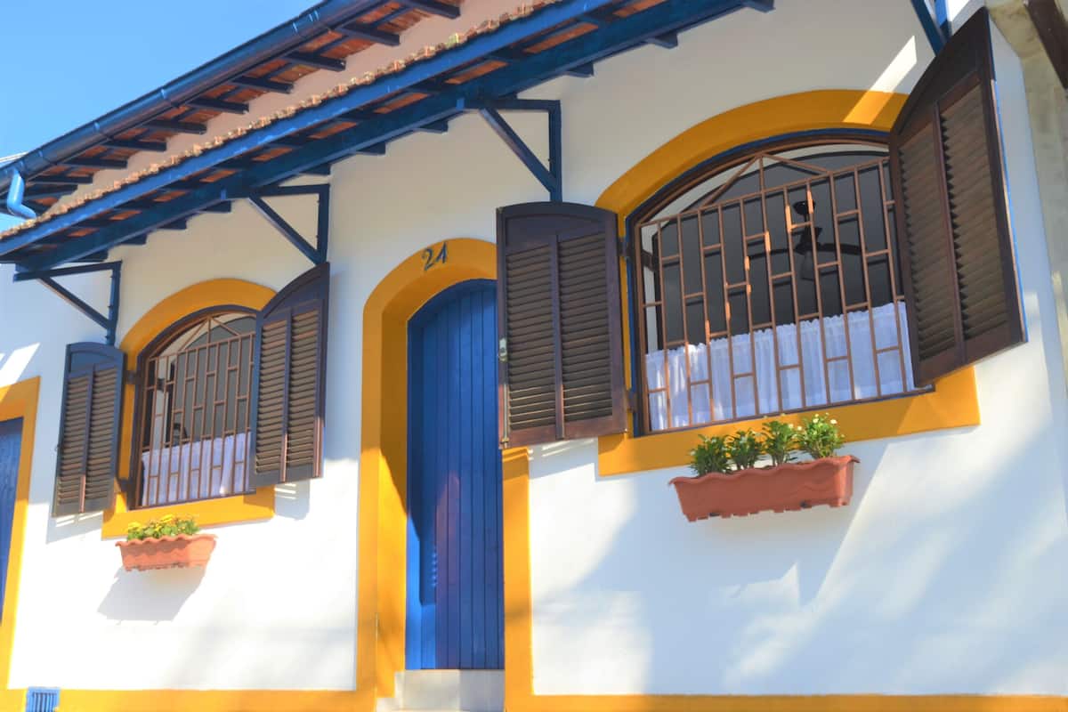 A building with a yellow and white facade, blue shutters, and a number '24' sign.