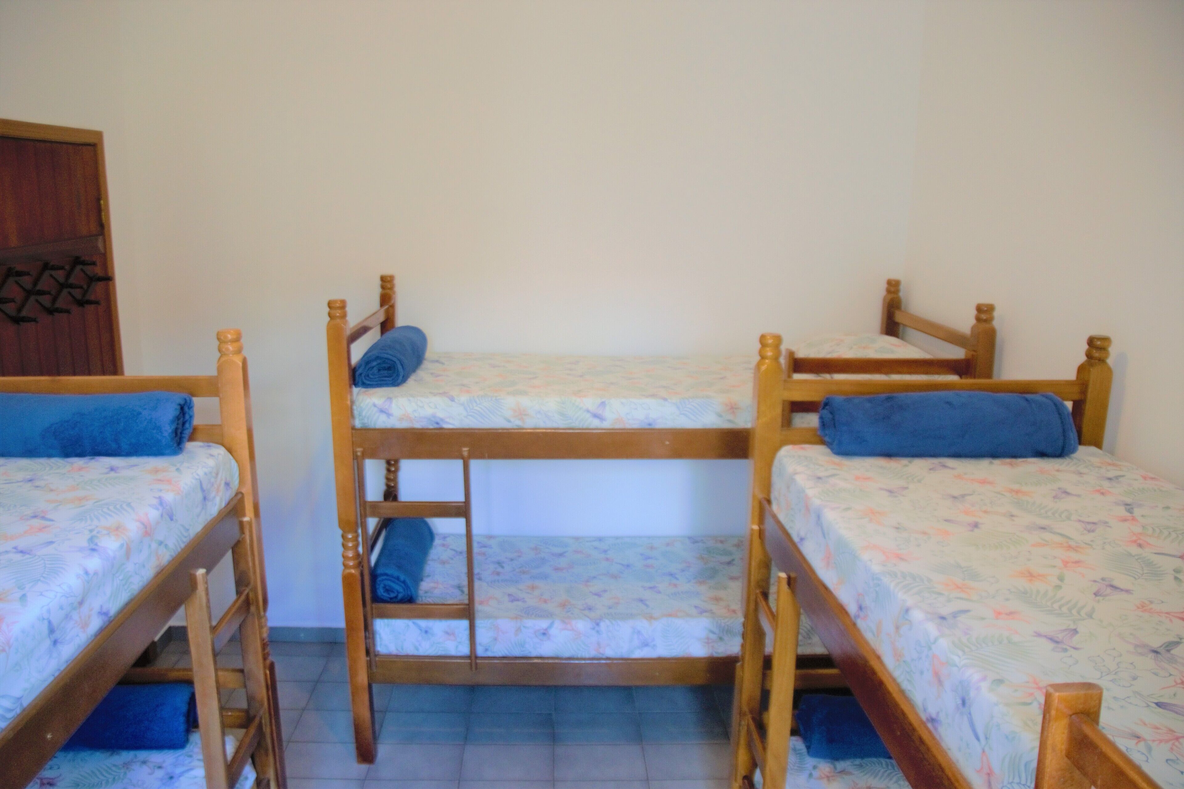 A room with three wooden bunk beds, each with a blue blanket.
