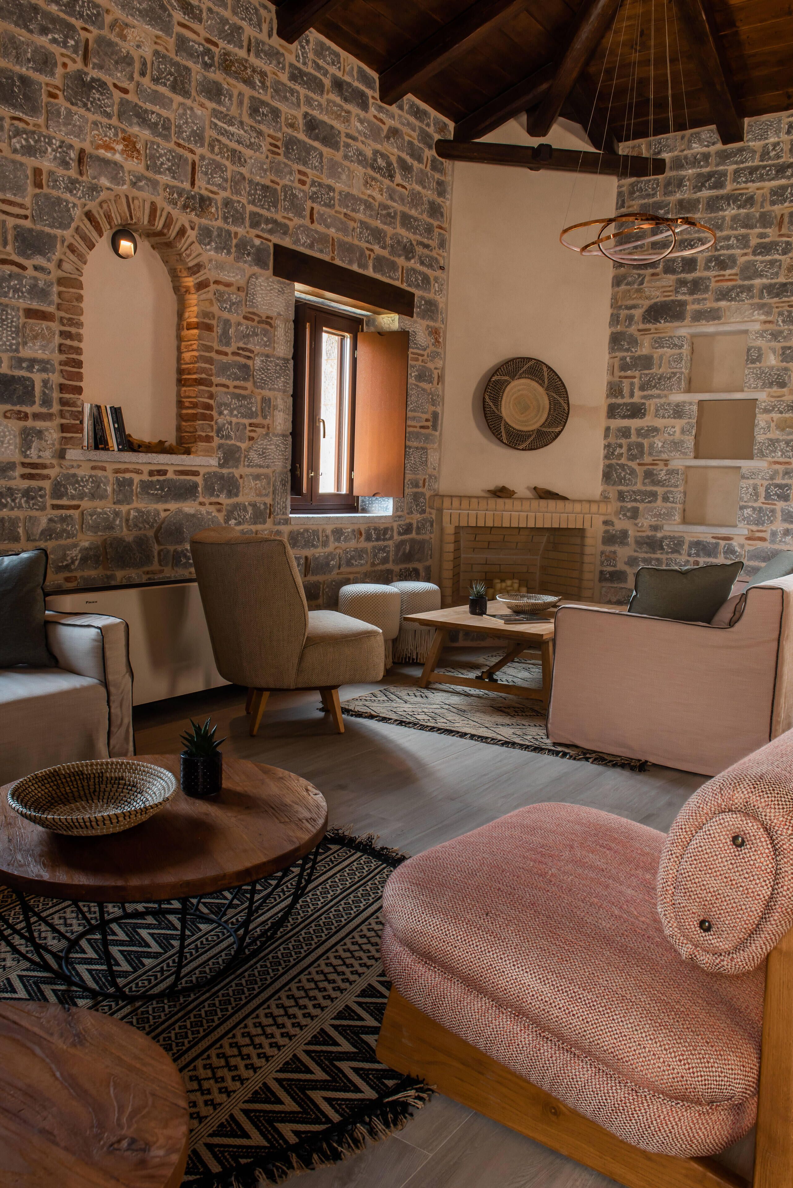 A cozy living room with stone walls, a fireplace, and comfortable seating.