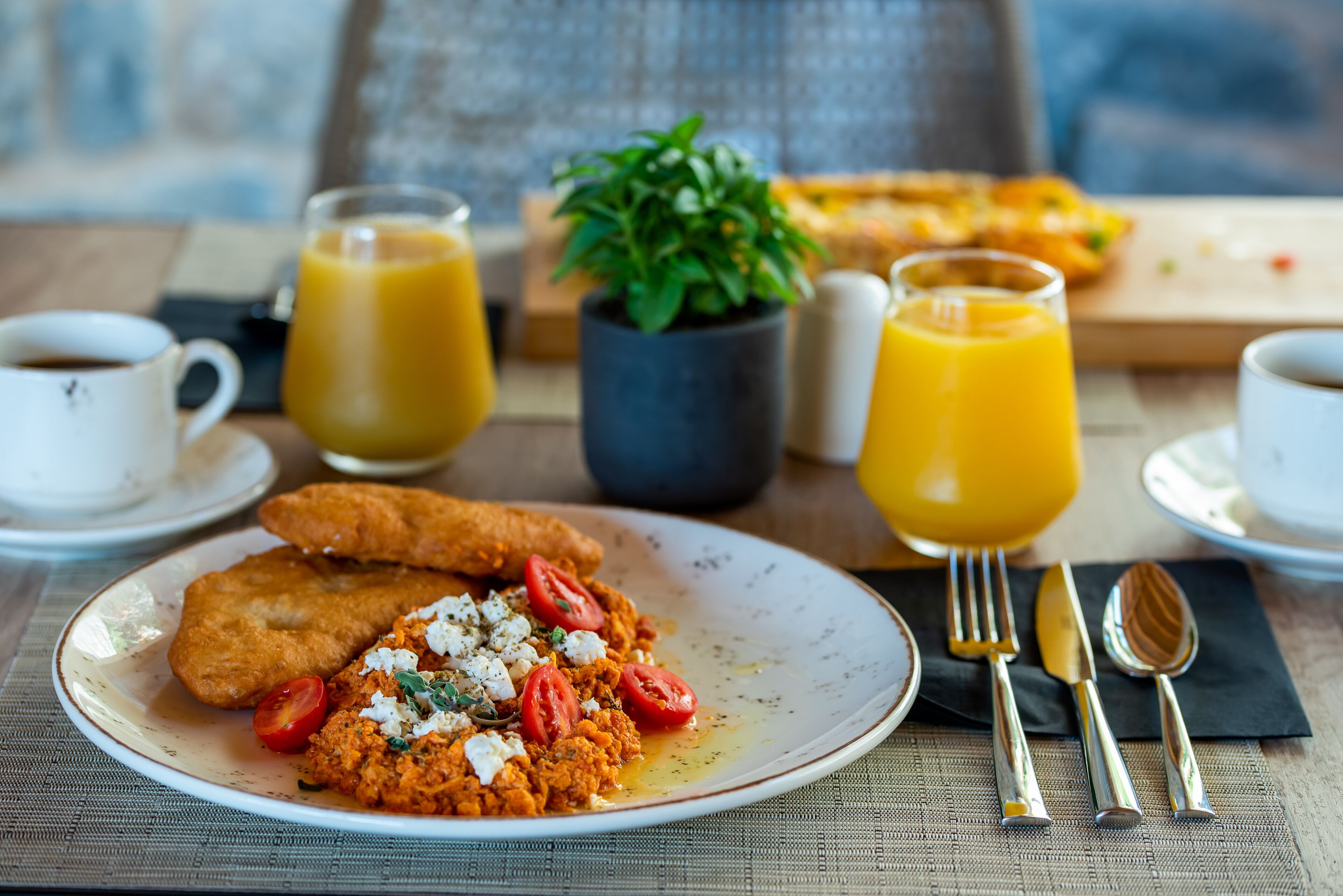 Un desayuno con un plato de comida, dos vasos de jugo de naranja y una taza de café.