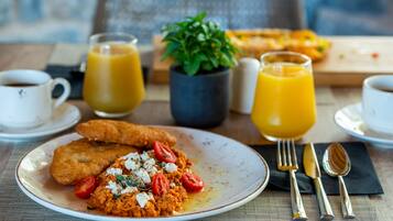 Un desayuno con un plato de comida, dos vasos de jugo de naranja y una taza de café.