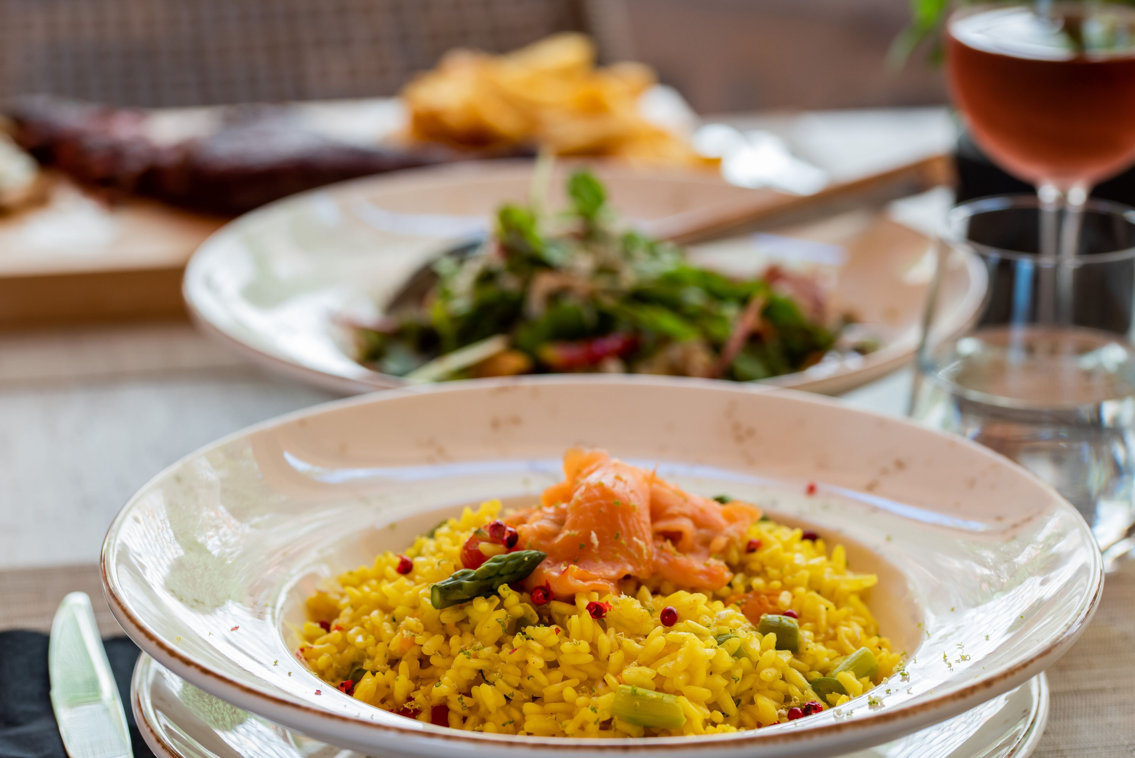 A dining table with a plate of yellow rice, green vegetables, and salmon.