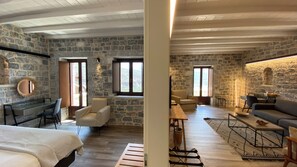 Una habitación amplia con paredes de piedra, techo de madera y ventanas grandes.