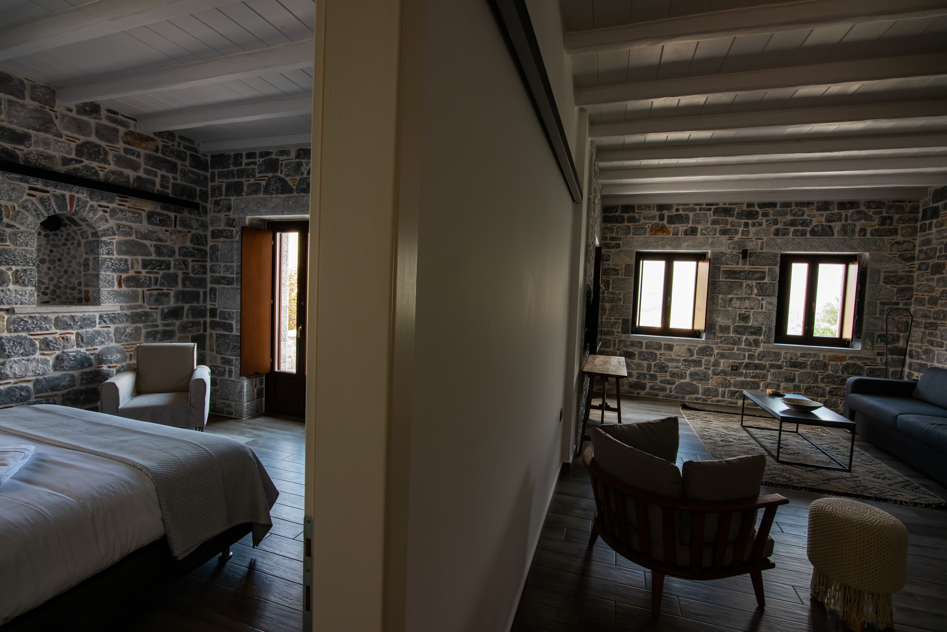Una habitación con paredes de piedra, una cama, suelo de madera, un sofá y una mesita.