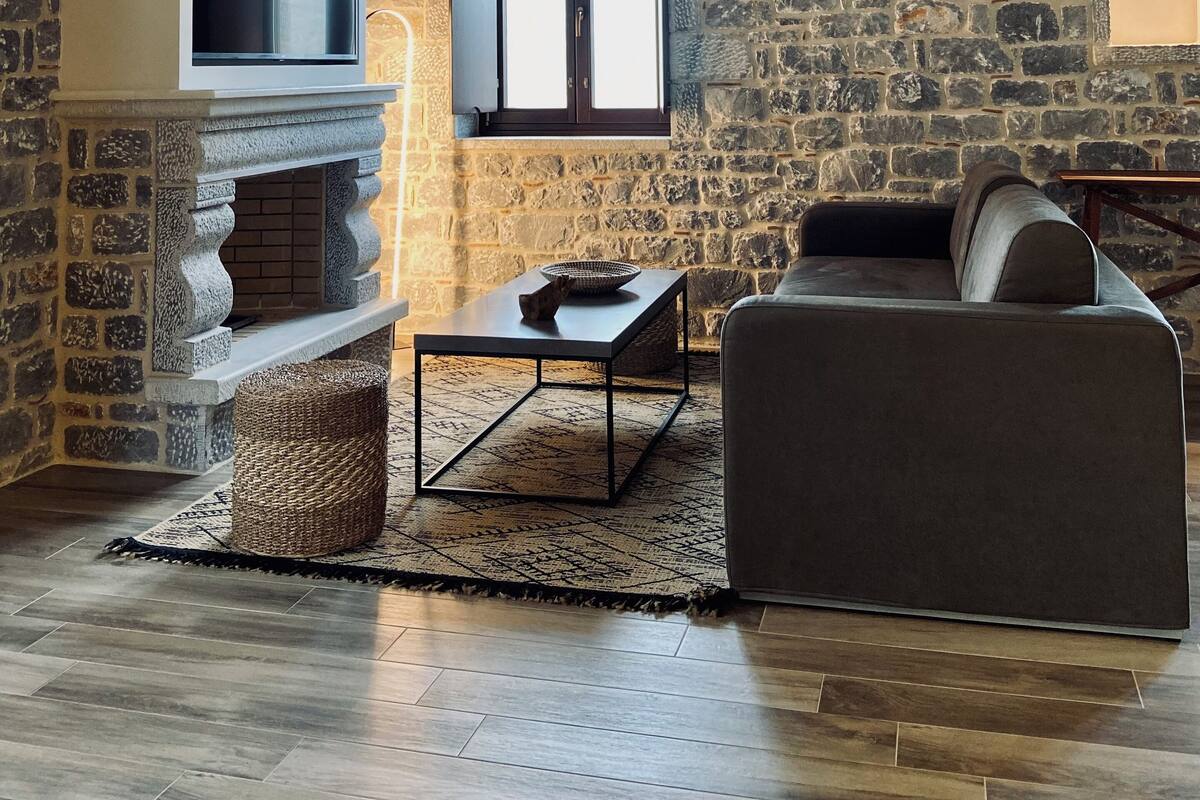 Ein gemütliches Wohnzimmer mit Steinwand, Kamin, Sofa und Fernseher.
