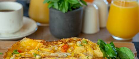 Un plato de desayuno con tortilla de verduras, una taza de café y un vaso de jugo de naranja.