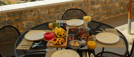 Une table dressée pour le petit-déjeuner, avec vue sur la montagne et la mer.